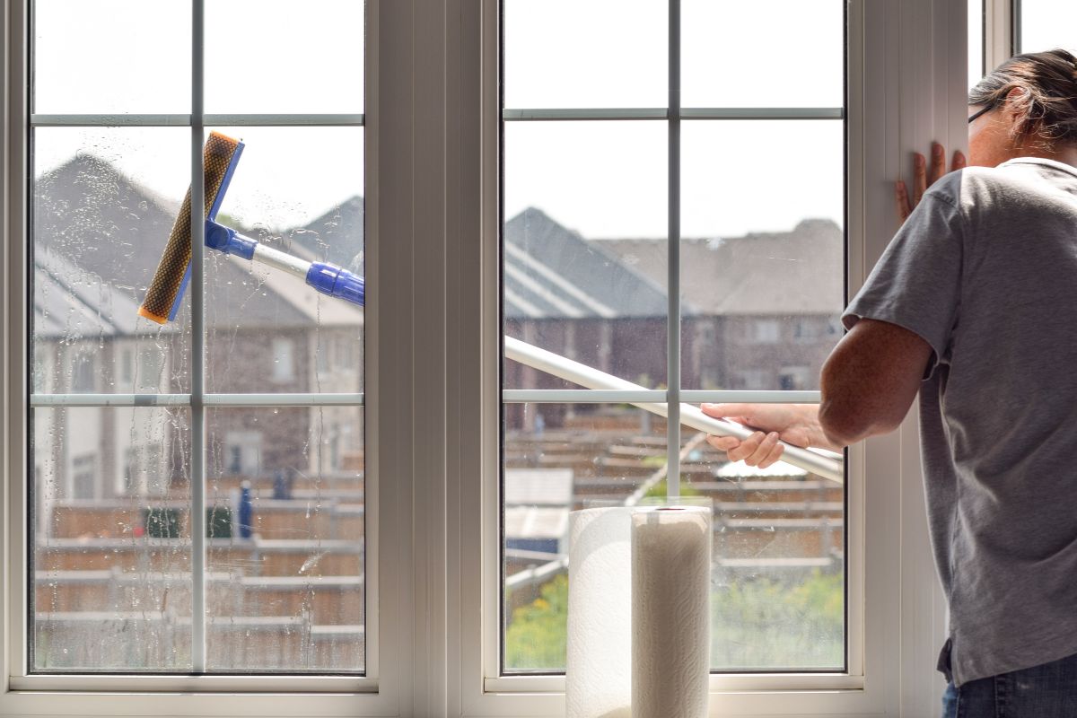 A man using a squeegee to clean a large window, focused on removing streaks for a clear view.