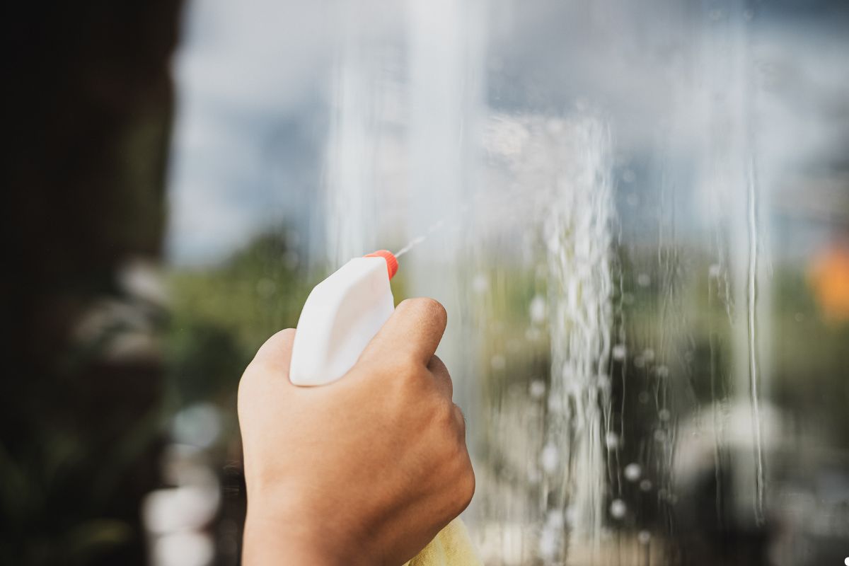 A person sprays water onto a glass window, creating a misty effect on the surface. 