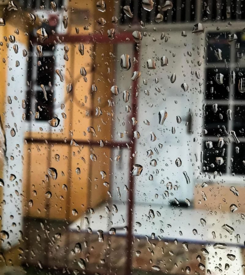 Close-up of raindrops on a house window, emphasizing the importance of professional storm window cleaning services.